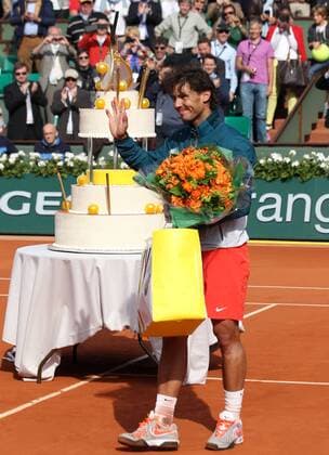 French Open 2013, Roland Garros,Paris,ITF Grand Slam Tennis Tournament, Geburtstagskind Rafael Nadal (ESP) mit Geschenktüte und Blumenstrauss,im Hintergrund steht die riesige Geburtstagstorte,Ganzkoerper,Hochformat,