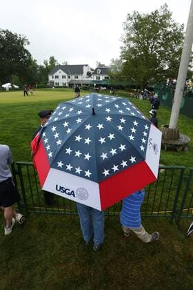 June 10 2013: Fans stand in the rain under a USGA umbrella while watching players on the 18th green in front of the Club House during monday s practice round at the 2013 U.S. Open hosted by Merion Golf Club in Ardmore, PA. GOLF: JUN 10 PGA Golf Herren - U.S. Open - Monday Practice Round Icon131829 EDITORIAL USE ONLY