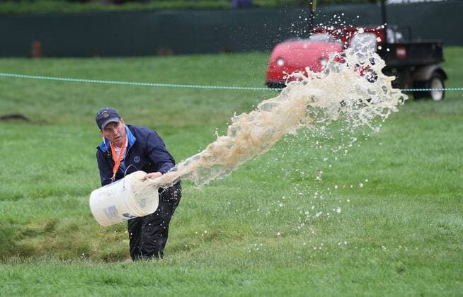 June 10, 2013 - Ardmore, PA, USA - A crew member bails water out of a bunker on the 1st hole during a practice round for the U.S. Open on Monday, June 10, 2013, At Meriod Golf Club in Ardmore, Pennsylvania. U.S. OPEN PRACTICE ROUNDS - ZUMAm67
