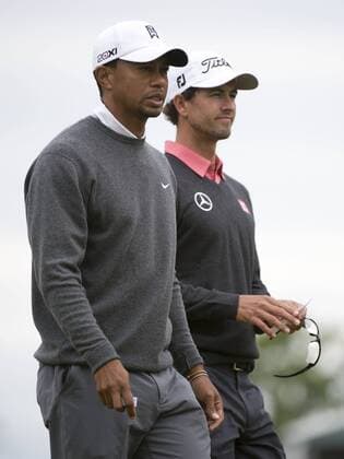 Tiger Woods and Adam Scott walk together on the 18th green during the continuation of the first round of the 113th U.S. Open Championship at Merion Golf Club in Ardmore, Pennsylvania on June 14, 2013.  PHI20130614303