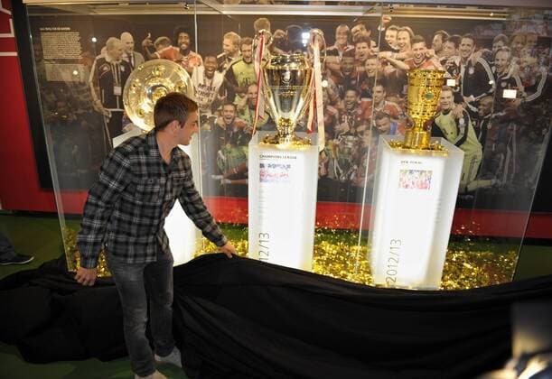 27.06.2013, Fussball 1.Bundesliga 2013 2014, FC Bayern München, Philipp Lahm (Bayern) eröffnet die Triple-Ecke im Bayern-Museum in der Allianz-Arena mit den drei Trophäen der vergangenen Saison.