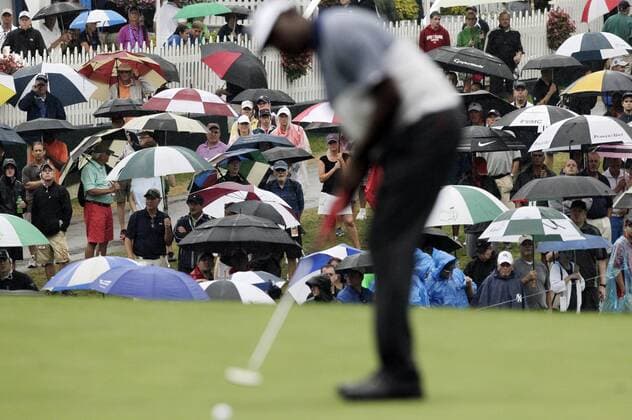 Spectators watch while holding umbrellas in the rain as Vijay Singh putts on the 18th green in the second round of the PGA Golf Herren Championship at Oak Hill Country Club in Rochester, New York on August 9, 2013.  NYP20130809102