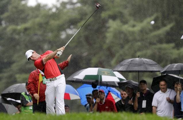 Spectators watch while holding umbrellas in the rain as Rory McIlroy hits his tee shot on the 18th hole in the second round of the PGA Golf Herren Championship at Oak Hill Country Club in Rochester, New York on August 9, 2013.  NYP20130809106