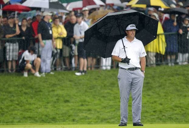 Phil Mickelson stands under an umbrella in the rain on the 14th tee box in the second round of the PGA Golf Herren Championship at Oak Hill Country Club in Rochester, New York on August 9, 2013.  NYP20130809120