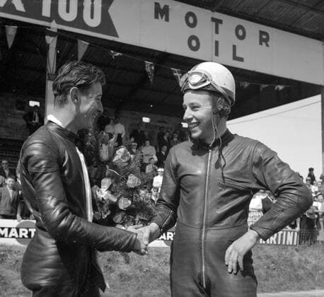 Mettet , Belgium : Britain s famous John Surtees ( right ) , who with his M V Augusta won the 350 cc event and the 500cc event at the Motor Cycling meet here , congratulates David Chadwick ( Norton ) , the first independent rider home in the 500 cc event . Chadwick came in third in this race and second in the 350 cc event . 6 May 1958 , Belgien  UnitedArchives00413748