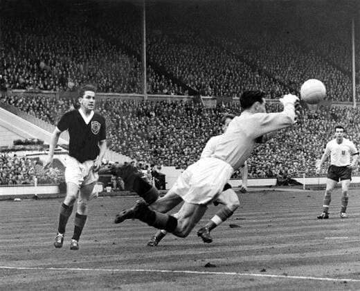 11th April 1959: England versus Scotland at Wembley. Photo shows: Brown, the Scots goalkeeper, dives out to clear from Charlton (half hidden) the England centre-forward.  UnitedArchives01009424