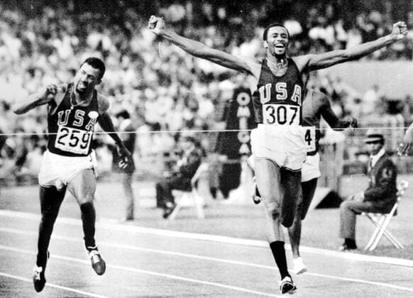 Mexico City: Tommie Smith, of Lemoore, Calif., Throws his arms up in victory as he its the tape to win a Gold Medal in the Men s 200 - meters final at the 19th Olympic Games her yesterday. his time of 19.8 seconds set a new world record. Running despite an injured leg muscle, he streaked past team mate John Carlos, of San Jose, Calif., (left), who was placed third behind Australia s Peter Norman, who won the Silver Medal 17 October 1968  UnitedArchives01024384
