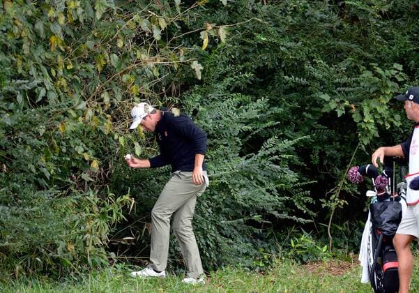 Adam Scott locates his golf ball in the woods on hole five before taking a drop during the third round of the PGA Golf Herren Tour Championship on September 21, 2013 at East Lake Golf Club in Atlanta. Scott scored a double bogey on the hole.  AJP2013092108