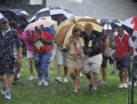 Fans head for shelter as heavy rain falls during a weather delay of the fourball matches at the 2013 Presidents Cup at Muirfield Village Golf Club in Dublin, Ohio on October 3, 2013.  BKX2013100338