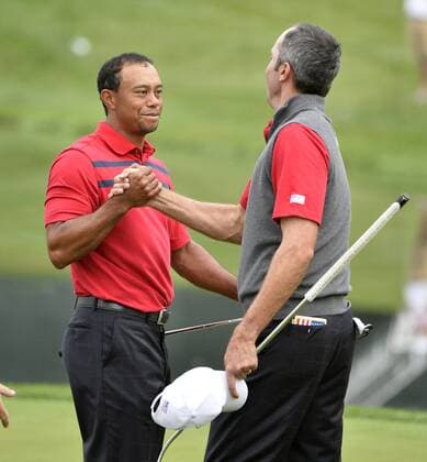 United States Team members Tiger Woods and Matt Kuchar celebrate their 4 and 2 win over International Team members Louis Oosthuizen and Charl Schwartzel, both of South Africa, on the 16th green during the second round foursome competition at the 2013 Presidents Cup at Muirfield Village Golf Club in Dublin, Ohio on October 5, 2013.  BKX2013100501