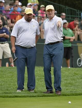 International Team member Brendon de Jonge of Zimbabwe (L) helps teammate Ernie Els of South Africa one up his putt on the sixth hole during the third round four-ball competition against the United States Team at the 2013 Presidents Cup at Muirfield Village Golf Club in Dublin, Ohio on October 5, 2013.  BKX2013100515