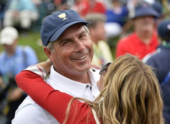 United States Team captain Fred Couples gets a hug from girlfriend Nadine Moze on the 18th green after the fifth round singles competition at the 2013 Presidents Cup at Muirfield Village Golf Club in Dublin, Ohio on October 6, 2013. The United States defeated the International Team 18.5 to 15.5 to retain the Presidents Cup.  BKX2013100627