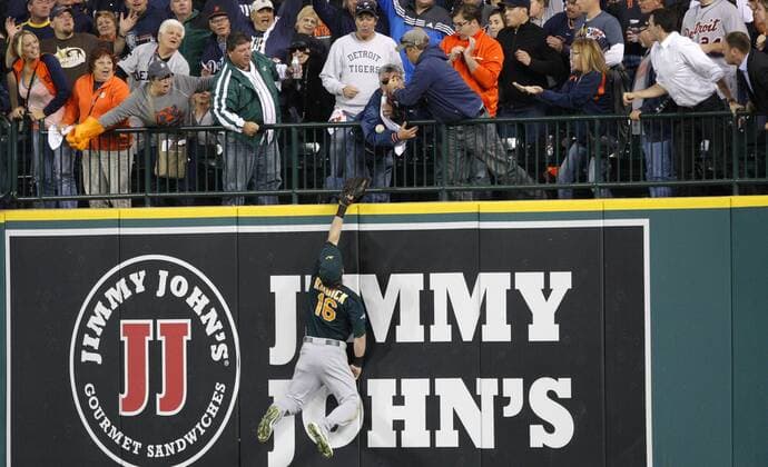 Oakland Athletics right fielder Josh Reddick and a fan reach for the solo home run ball during the seventh inning of game 4 of the ALDS game at Comerica Park in Detroit on October 8, 2013.  DET20131008125