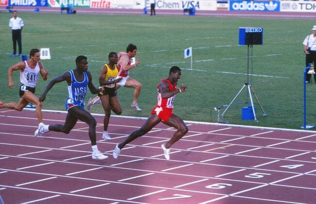 Athletics - 1987 IAAF Rome World Championships - Men s 100m Final Canada s Ben Johnson (red) shocks the world by defeating the USA s Carl Lewis (in blue) to win the race in a new World Record of 9.83s at the Stadio Olimpico. Jamaica s Raymond Stewart (yellow) is also pictured. 30 08 1987 