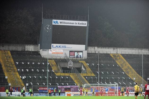 KFC Uerdingen 05 --- Fussball --- Regionalliga West --- 12.11.2013 Grotenburg-Stadion Krefeld, leere, gesperrte Osttribüne, Ostkurve, darauf Kreuze und ein Banner mit der Aufschrift R.I.P. Ost geboren 1986 gestorben 2013, davor Aktion auf dem Spielfeld, Anzeigetafel mit der Aufschrift Willkommen in Krefeld, außer Betrieb, falsche Uhrzeit, Stadionansicht, Innenansicht KFC Uerdingen 05 --- Fussball --- Regionalliga West --- 12.11.2013