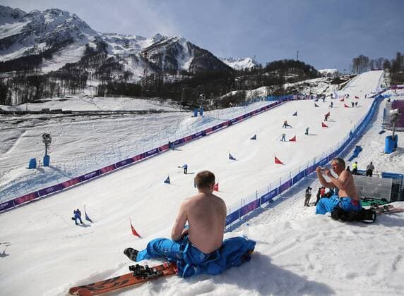 Feb. 22, 2014 - Sochi, RUS - Course workers take their shirts off to enjoy warm weather during the snowboard parallel slalom competition at the Rosa Khutor Extreme Park during the Winter Olympics in Sochi, Russia, Saturday, Feb. 22, 2014. Parallel Slalom Snowboarding - ZUMAm67