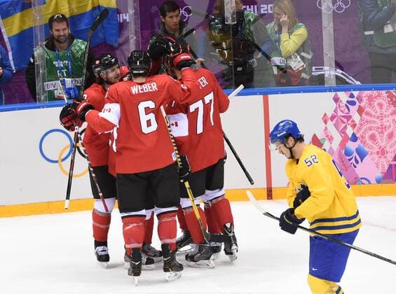 Canada s Jonathan Toews (obscured) celebrates his first period goal with Canada s Jeff Carter (77) and Shea Weber (6) during their gold medal game against Sweden at the Sochi 2014 Winter Olympics on February 23, 2014 in Sochi, Russia.  OLY2014023703
