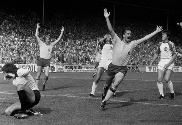 Rot-Weiss Essen - Borussia Mönchengladbach 1:3 30.8.1975. Uli Stielike (Borussia Mönchengladbach) jubelt nach dem Eigentor durch Gerd Wörmer (RWE), der die Hände über dem Kopf zusammenschlägt. Links: Tw. Jürgen Rynio. Rechts: Gerd Wieczorkowski (alle RWE). Im Hintergrund: Henning Jensen (BMG). HM