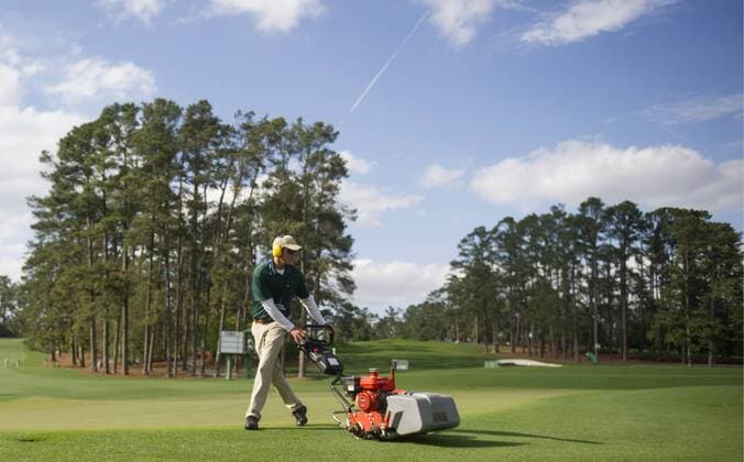 A member of the grounds crew cuts the grass following a practice round prior to the Masters golf tournament at Augusta National Golf Club in Augusta, George, April 8, 2014.  AUG20140408369