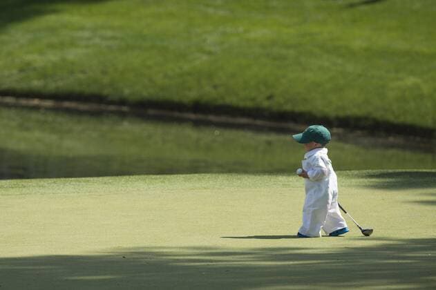 Scott Staulings son Finn carries a mini golf club as he walks on the ninth green during the Par 3 Contest during the Masters Tournament at Augusta National Golf Club in Augusta, Georgia, April 8, 2014.  AUG20140409344