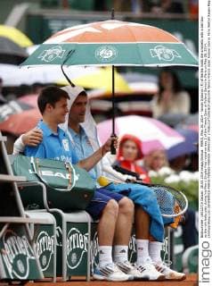 PARIS, May 26, 2014 - Novak Djokovic (R) of Serbia holds the umbrella with a ball boy as the rain halts play during his Men s Singles first round on day 2 of the French Open at Roland Garros in Paris on May 26, 2014. (Xinhua Wang Lili) (SP)FRANCE-PARIS-TENNIS-FRENCH OPEN-DAY 2 