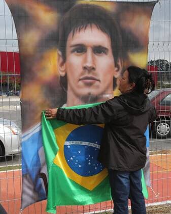 (140611) -- SAO PAULO, June 11, 2014 (Xinhua) -- A fan covers a poster of Argentina s soccer player Lionel Messi with a Brazilian national flag in the Arena de Sao Paulo stadium in Itaquera on the east side of Sao Paulo, Brazil, on June 11, 2014. The Brazilian national soccer team will face Croatia on Thursday in the opening match of 2014 FIFA World Cup. (Xinhua AGENCIA ESTADO) (rh) (SP)BRAZIL-SAO PAULO-WORLD CUP 2014-FANS 