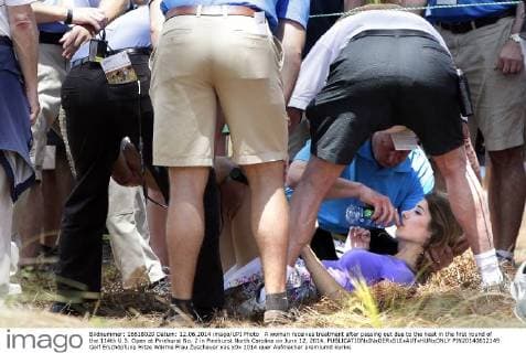 A woman receives treatment after passing out due to the heat in the first round of the 114th U.S. Open at Pinehurst No. 2 in Pinehurst North Carolina on June 12, 2014.  PIN20140612149