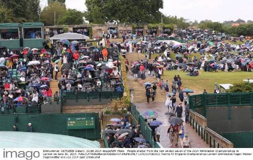 People shelter from the rain on day seven of the 2014 Wimbledon Championships in London on June 30, 2014.  LON2014063021