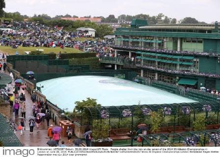 People shelter from the rain on day seven of the 2014 Wimbledon Championships in London on June 30, 2014.  LON2014063025