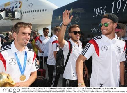 BERLIN, GERMANY - JULY 15: Philipp Lahm with the cup, Mario Götze and Benedikt Höwedes looks happy after the flight on July 15, 2014 in Berlin, Germany. Local Caption Philipp Lahm; Mario Götze; Benedikt Höwedes