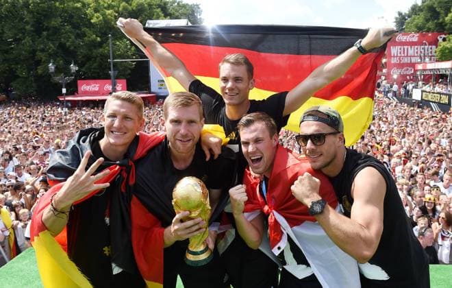 Bastian SCHWEINSTEIGER Per MERTESACKER , Torwart Manuel NEUER , Kevin Grosskreutz und Lukas PODOLSKI mit WM-Pokal und Deutschlandfahne Empfang WM-Party Feier der deutschen Fussball Nationalmannschaft auf die Fanmeile am Brandenburger Tor in Berlin- Fanmeile in Berlin Deutschland am 15. Juli 2014 