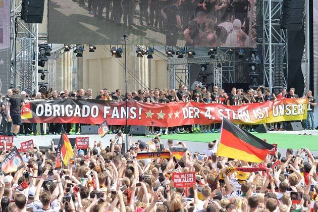 Empfang der Weltmeister --- Fussball --- International --- 15.07.2014 Die deutsche Nationalmannschaft präsentiert ein Banner mit der Aufschrift: Obrigado Fans! Der 4. Stern ist unser!, davor jubelnde Fans, Anhänger, Anhaenger, Groupies, Zuschauer, Jubel, Freude, Mannschaft, Team