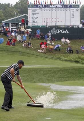 A groundskeeper squeegees a landing area on the 18th fairway after a thunderstorm forced a suspension in play of the final round of the 96th PGA Golf Herren Championship at Valhalla Country Club on August 10, 2014 in Louisville, Kentucky.  LOU2014081001