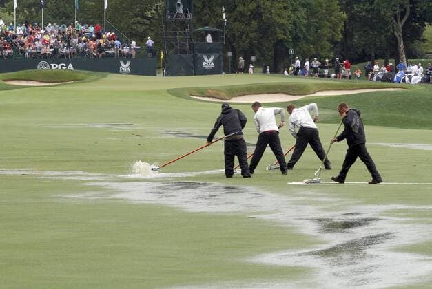 Groundskeepers squeegee the first fairway after a thunderstorm forced a suspension in play of the final round of the 96th PGA Golf Herren Championship at Valhalla Country Club on August 10, 2014 in Louisville, Kentucky.  LOU2014081002