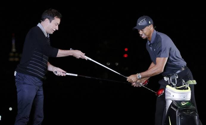 Tiger Woods hands Jimmy Fallon a golf club at the launch of the new Nike Vapor Iron Franchise at Liberty National Golf Club in Jersey City, NJ on August 18, 2014. The Vapor Iron Franchise consists of 3 sets of golf club irons; The Vapor Pro, Vapor Pro Combo and Vapor Speed.  NYP20140818107