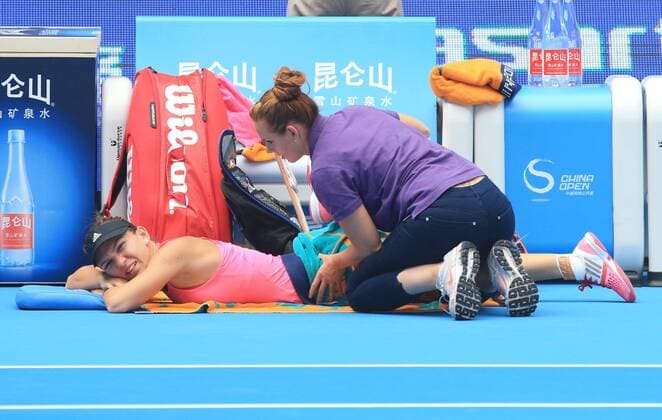 (141002) -- BEIJING, Oct. 2, 2014 -- Romania s Simona Halep (L) gets medical treatment during the women s third round match at the 2014 China Open in Beijing, capital of China, on Oct. 2, 2014. XingxGuangli 