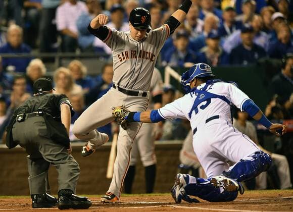 Kansas City Royals catcher Salvador Perez tags out San Francisco Giants catcher Buster Posey who attempted to score from first base on teammate s Pablo Sandoval RBI double in the first inning of game 1 of the World Series at Kaufman Stadium in Kansas City, Missouri on October 21, 2014.  KCP2014102108