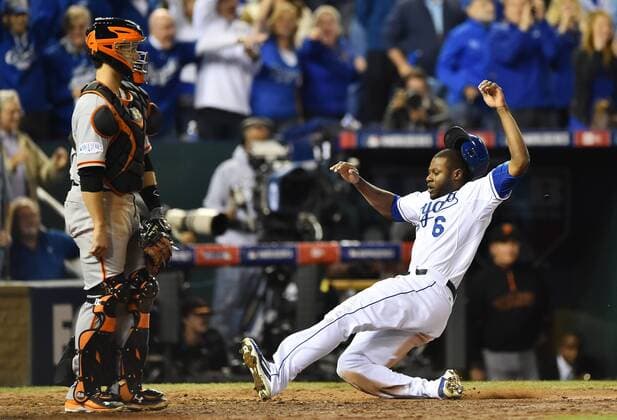 Kansas City Royals Lorenzo Cain scores on teammate s Billy Butlers RBI single against the San Francisco Giants during the sixth inning of game 2 of the World Series at Kaufman Stadium in Kansas City, Missouri on October 22, 2014. The Giants catcher Buster Posey stands while Cain scores. San Francisco holds a 1-0 series lead over Kansas City.  KCP2014102247