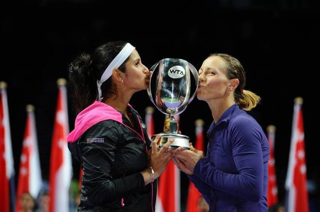 Cara Black (R) of Zimbabwe and Sania Mirza of India kiss the trophy during the awarding ceremony after the doubles final match of WTA Tennis Damen Finals in Singapore Indoor Stadium, Oct. 26, 2014. (SP)SINGAPORE-TENNIS-WTA-DOUBLES-FINAL ThenxChihxWey 