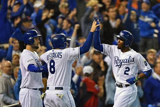 Kansas City Royals shortstop Alcides Escobar (@) high fives with teammates Eric Hosmer (L) and Mike Moustakas after scoring against the San Francisco Giants during the second inning of game 6 of the World Series at Kaufman Stadium in Kansas City, Missouri on October 28, 2014. The Giants hold a 3-2 series lead and need only one win against the Royals to win the World Series.  KCP2014102843