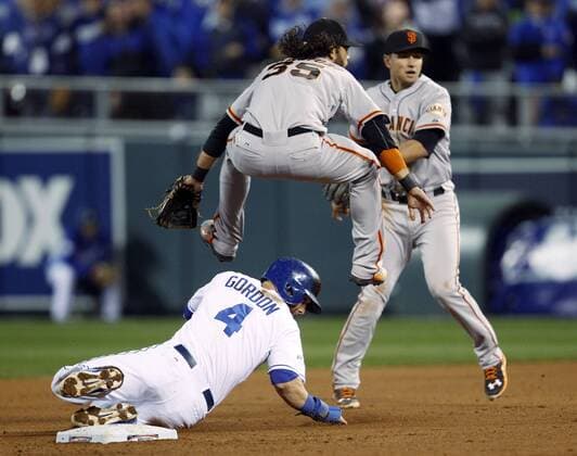 San Francisco Giants shortstop Brandon Crawford (R) leaps over Kansas City Royals Alex Gordon after forcing Gordon out at second base as throwing to first to complete a double play on a ground ball hit by Salvador Perez during the fourth inning of game 7 of the World Series at Kauffman Stadium in Kansas City, Missouri on October 29, 2014.  KCP20141029201