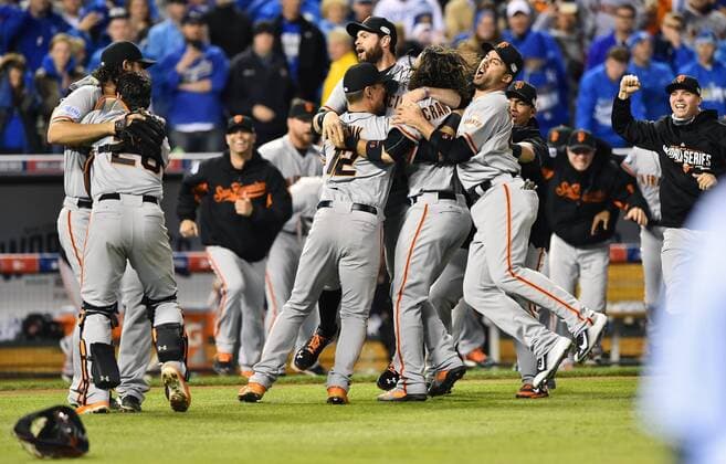 San Francisco Giants catcher Buster Posey hugs MVP Madison Bumgarner (L) as the Giants rush the field after final out against the Kansas City Royals in game 7 of the World Series at Kauffman Stadium in Kansas City, Missouri on October 29, 2014. San Francisco wins the World Series defeating Kansas City 3-2.  KCP2014102981