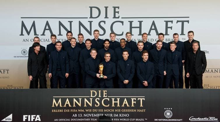 Gruppenbild - Die Nationalspieler posieren auf dem Roten Teppich. hintere Reihe vlnr: Hans-Dieter FLICK, Erik DURM, Mats HUMMELS, Miroslav KLOSE, Per MERTESACKER, Matthias GINTER, Christoph KRAMER, Benedikt HOEWEDES, Thomas MÜLLER, Kevin GROSSKREUTZ, Teammanager Oliver BIERHOFF mittlere Reihe vlnr: Bundestrainer Joachim LÖW, Lukas PODOLSKI, Torwart Manuel NEUER, Torwart Roman WEIDENFELLER, Sami KHEDIRA, Jerome BOATENG, Shkodran MUSTAFI, Torwart Ron-Robert ZIELER, Toni KROOS, Torwarttrainer Andreas KÖPKE vordere Reihe vlnr: Bastian SCHWEINSTEIGER und Philipp LAHM halten gemeinsam den Weltmeisterpokal, Mesut OEZIL, Mario GÖTZE Vorstellung und Weltpremiere des Dokumentarfilmes Die Mannschaft im CineStar Sony Center in Berlin, Deutschland am 10.11.2014, die Deutsche Fussballnationalmannschaft zeigt sich in einem Film zur Fussballweltmeisterschaft 2014 in Brasilien.