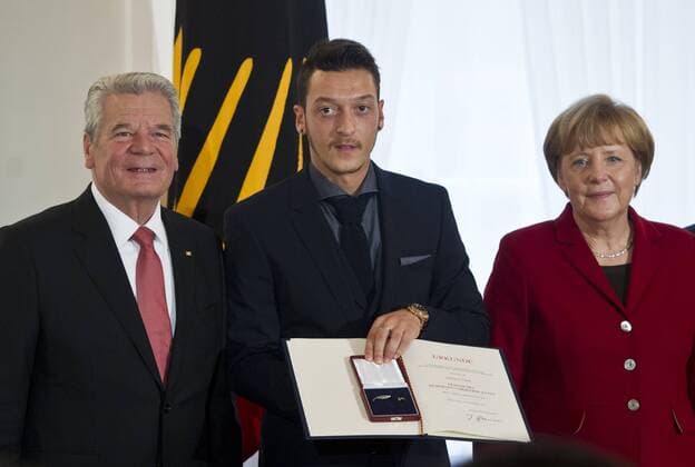 Mesut ÖZIL bekommt das Silberne Lorbeerblatt von Bundespräsident Joachim GAUCK und Bundeskanzlerin Angela MERKEL (vl) überreicht. Sportlerauszeichnung - Verleihung des Silbernen Lorbeerblattes durch den Bundespräsidenten für die deutsche Fussballnationalmannschaft im Schloss Bellevue in Berlin, Deutschland am 10.11.2014.