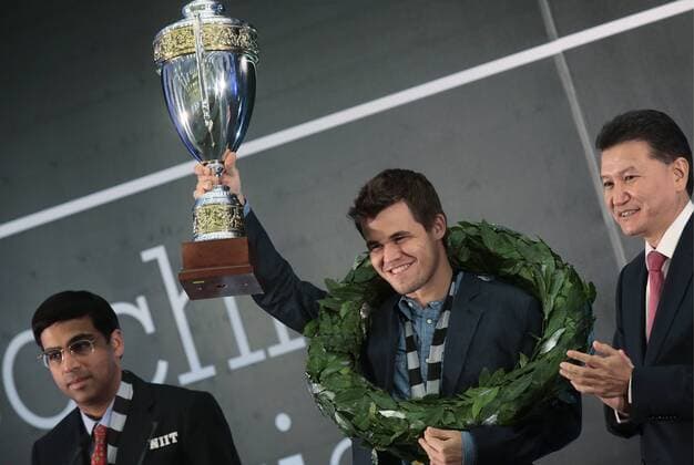 SOCHI, RUSSIA.NOVEMBER 25, 2014. Indian chess player Viswanathan (Vishy) Anand, left, and Kirsan Ilyumzhinov, the president of the World Chess Federation (FIDE), right, look on as chess champion Magnus Carlsen (C) of Norway holds up his trophy after winning the FIDE World Chess Championship 2014.  premiumd RE155C9A