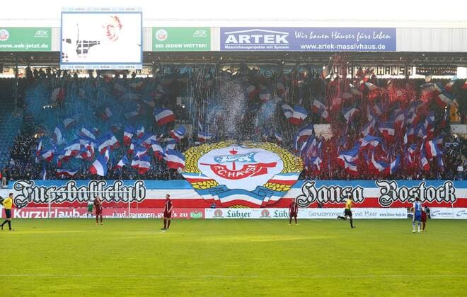 Fußball, Stadiongeschichte FC Hansa Rostock Samstag 29.11.2014, 3. Liga, Saison 2014 15 - 19. Spieltag in der Rostocker DKB-Arena, FC Hansa Rostock, Die Rostocker Fans unterstützen ihr Team von der Südtribüne Heimkurve aus Choreografie mit dem Spruchband: Fußballclub Hansa Rostock mit dem Vereinslogo als Blockfahne und dazu viele schwarzweißrote Fahnen und Konfettishooter