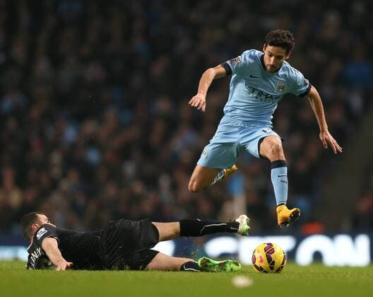 Jesus Navas of Manchester City jumps over a tackle by Dean Marney of Burnley - Barclays Premier League - Manchester City vs Burnley FC - Etihad Stadium - Manchester - England - 28th December 2014 - Picture Simon Bellis Sportimage EDITORIAL USE ONLY. No use with unauthorised audio, video, data, fixture lists, club league logos or live services. Online in-match use limited to 120 images, no video emulation. No use in betting, games or single club league player publications.