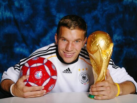 Lukas Podolski im Trikot der deutschen Nationalmannschaft mit WM-Pokal