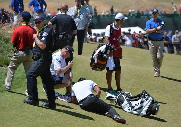 Jason Day of Australia lies collapsed on the ground as caddie Colin Swatton crouches over him on the ninth hole, his last of the day, in the second round of the 115th U.S. Open Championship at Chambers Bay on June 19, 2015 in University Place, Washington. Day recovered to putt out and finish his round.  SEA20150619035 KEVINxDIETSCH
