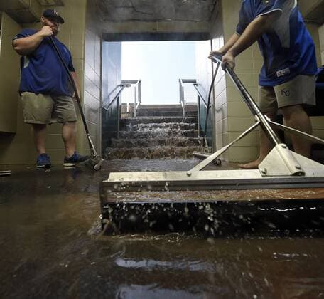 July 6, 2015 - Kansas City, MO, USA - Kansas City Royals tarp crew members try to keep runoff from reaching the batting cages as water cascades from the dugout before the cancellation of the baseball game against the Tampa Bay Rays on Monday, July 6, 2015, at Kauffman Stadium in Kansas City, Mo. Tampa Bay Rays at Kansas City Royals game rained out - ZUMAm67_